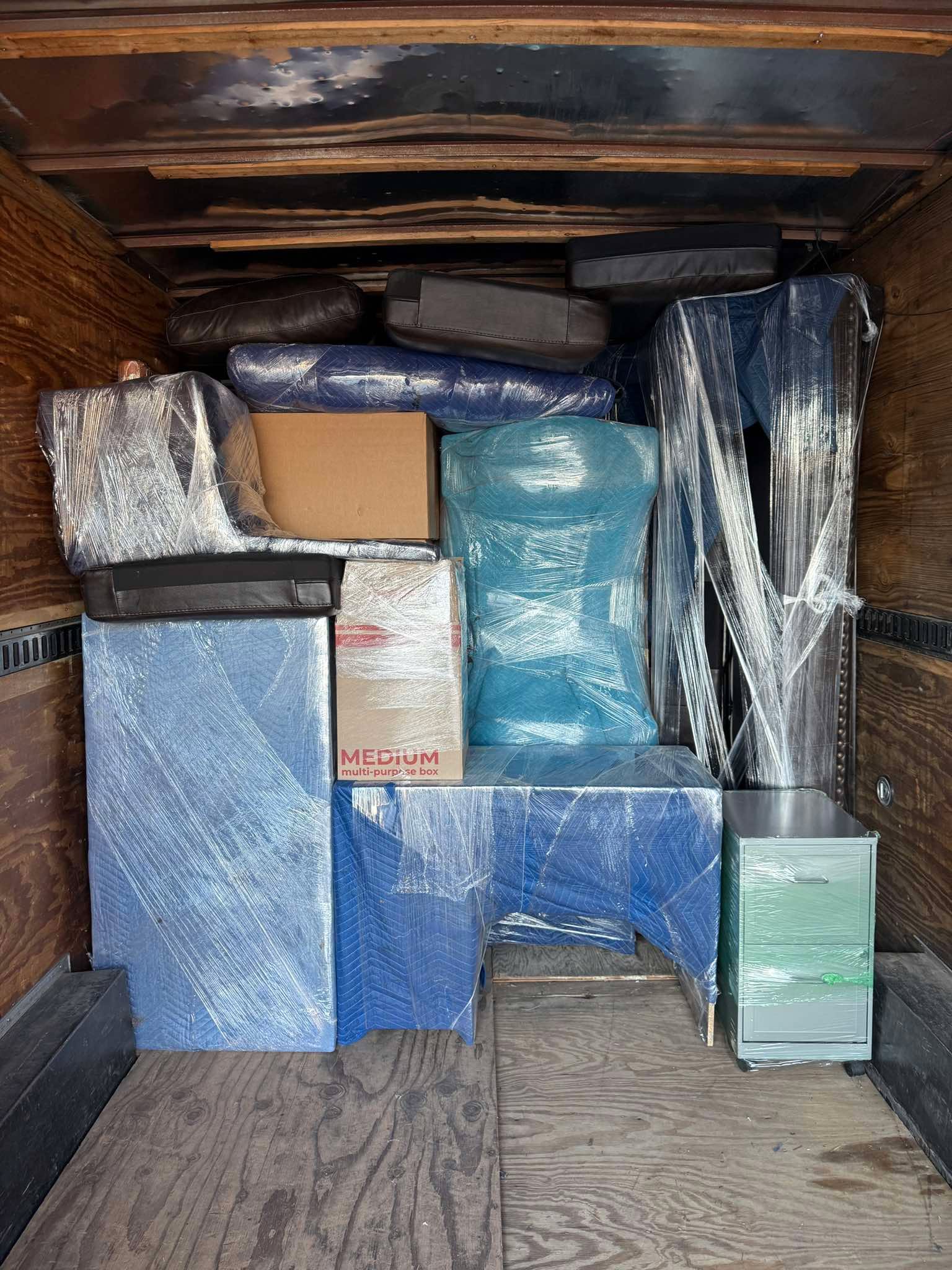 Furniture wrapped in moving blankets inside a trailer
